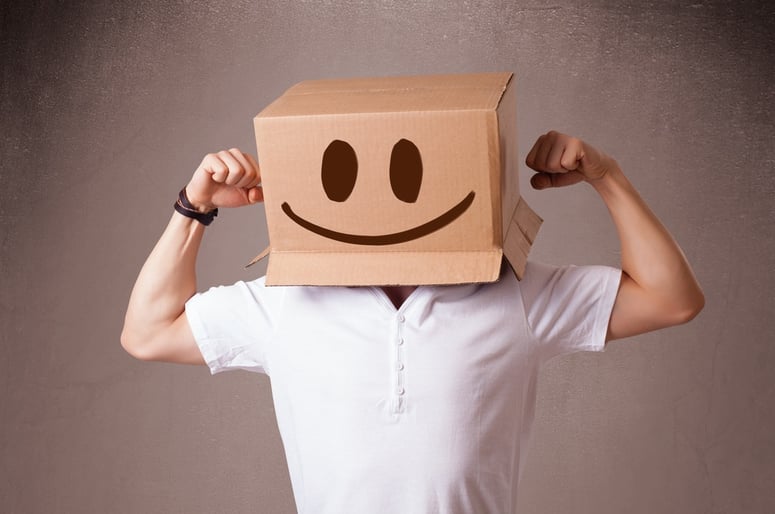 Young man standing and gesturing with a cardboard box on his head with smiley face.jpeg