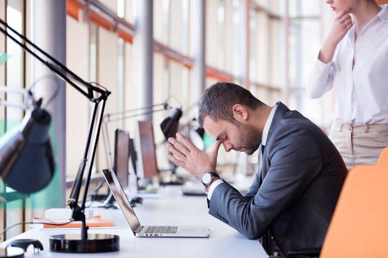 frustrated young business man working on laptop computer at office.jpeg